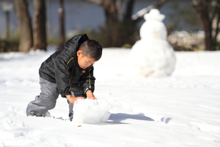 Japanese boy making snowmanの写真素材