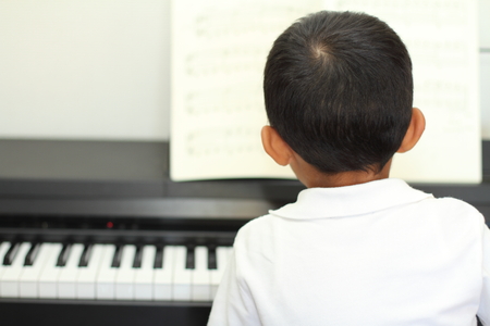 Japanese boy playing a piano (5 years old)の写真素材