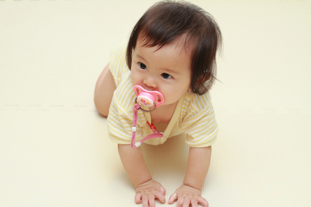 Japanese baby girl sucking on a pacifier (0 year old)の写真素材