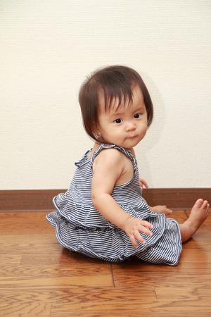 Japanese baby girl sitting on the floor (0 year old)の写真素材