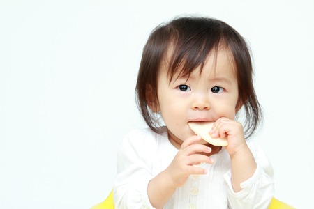 Japanese baby girl eating rice cracker (0 year old)の写真素材