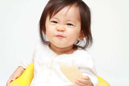 Japanese baby girl eating rice cracker (0 year old)の写真素材