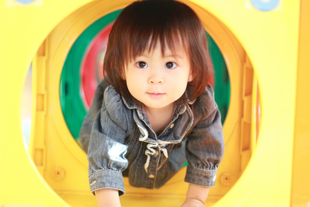 Japanese baby girl passing through a tunnel (1 year old)の写真素材
