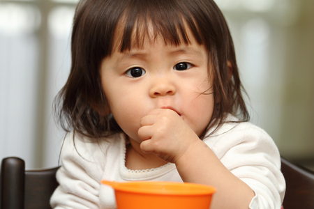 Japanese baby girl eating cereal (1 year old)の写真素材
