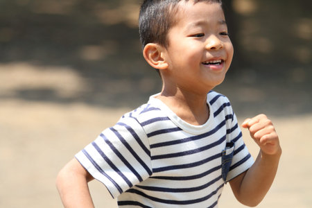 Japanese boy running on the grass?(first grade at elementary school)の写真素材