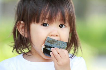 Japanese girl eating rice ball (1 year old)の写真素材