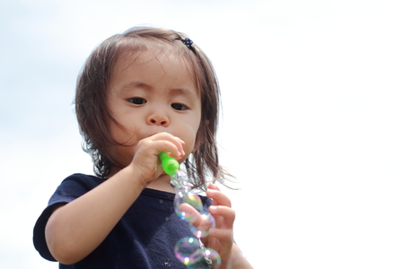 Japanese girl playing with bubble (1 year old)の写真素材