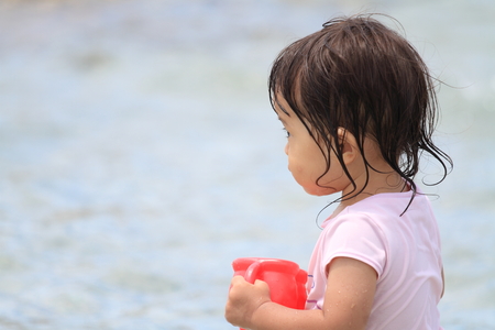 Japanese girl playing with water with watering pot (1 year old)の写真素材