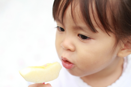 Japanese girl eating an apple (1 year old)の写真素材