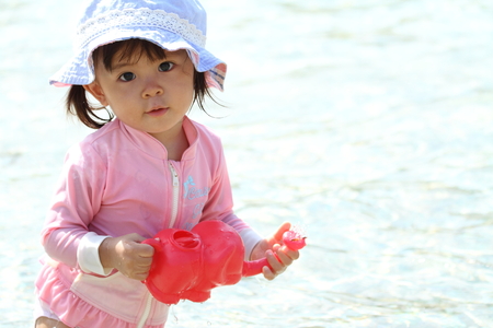 Japanese girl playing with water with watering pot (1 year old)の写真素材