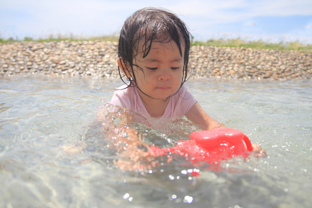 Japanese girl playing with water with watering pot (1 year old)の写真素材