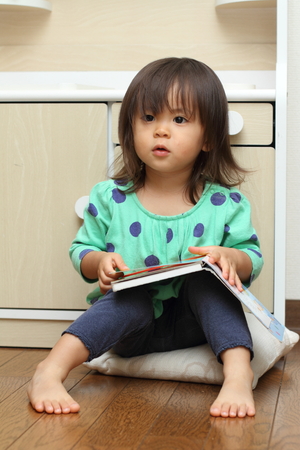 Japanese girl reading a picture book (1 year old)の写真素材