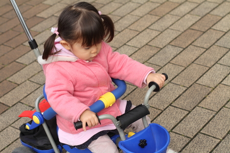 Japanese girl riding on the tricycle (2 years old)の写真素材