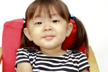 Japanese girl sitting on the chair (2 years old) (white back)の写真素材