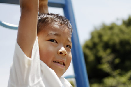 Japanese boy playing with a monkey bars (second grade at elementary school)