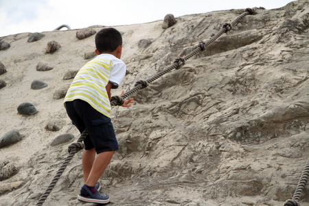 Japanese boy climbing on the wall (second grade at elementary school)の写真素材