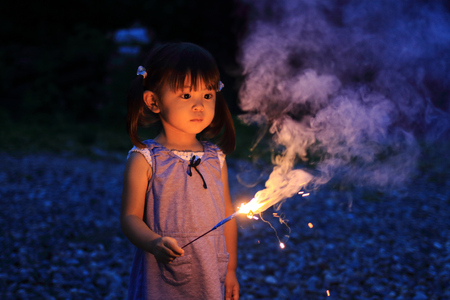 Japanese girl doing handheld fireworks (2 years old)の写真素材