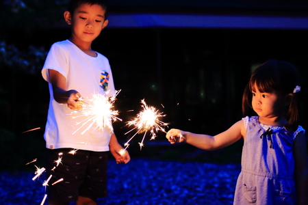 Japanese brother and sister doing handheld fireworks (7 years old boy and 2 years old girl)の写真素材