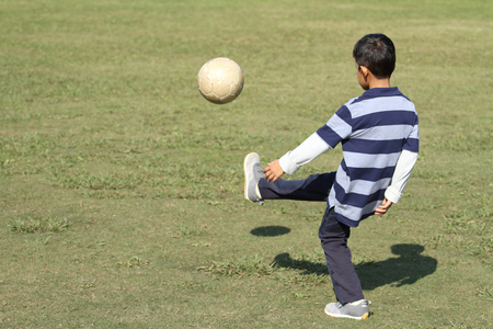 Japanese boy playing with soccer ball (second grade at elementary school)の写真素材