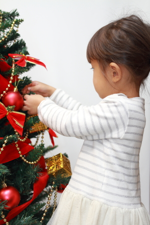 Japanese girl decorating Christmas tree (3 years old)の写真素材
