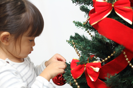 Japanese girl decorating Christmas tree (3 years old)の写真素材