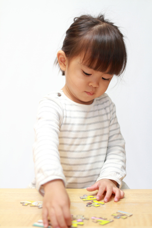 Japanese girl doing jigsaw puzzle (3 years old)の写真素材