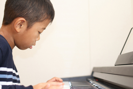 Japanese boy playing a piano (second grade at elementary school)の写真素材