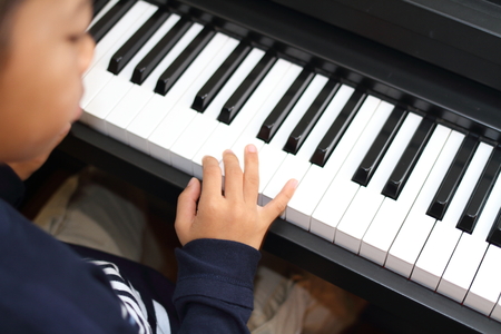 Japanese boy playing a piano (second grade at elementary school)の写真素材