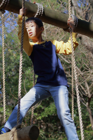 Japanese boy playing at outdoor obstacle course (third grade at elementary school)の写真素材