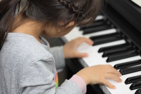 Japanese girl playing a piano (5 years old)の写真素材