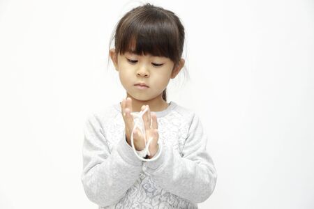Japanese girl playing with cat's cradle (white back) (5 years old)の写真素材