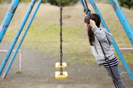 Japanese girl standing on the swing (5 years old)の写真素材