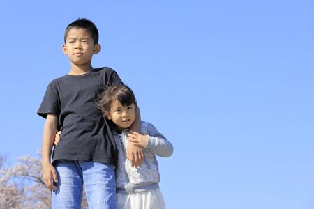 Japanese brother and sister and cherry blossoms (10 years old boy and 5 years old girl)の写真素材