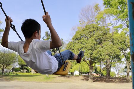 Japanese boy on the swing (appearance from behind) (fifth grade at elementary school)の写真素材