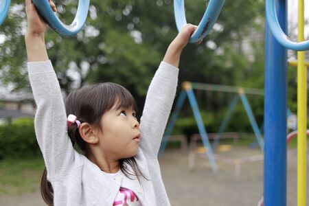 Japanese girl playing with a monkey bars (5 years old)の写真素材