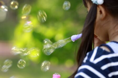Japanese girl playing with bubble in the green (appearance from behind) (5 years old)の写真素材