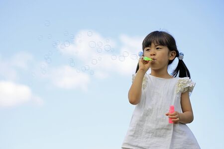 Japanese girl playing with bubble under the blue sky (5 years old)の写真素材