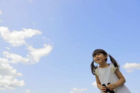 Japanese girl with opera glass under the blue sky (5 years old)の写真素材