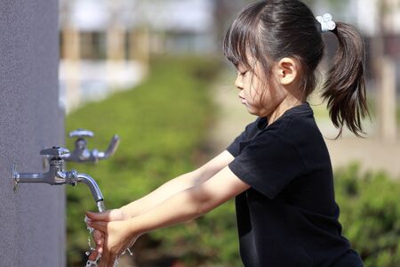 Japanese girl washing her hands at the park (5 years old)の写真素材