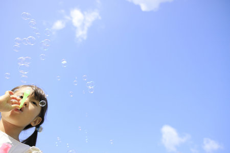 Japanese girl playing with bubble under the blue sky (5 years old)