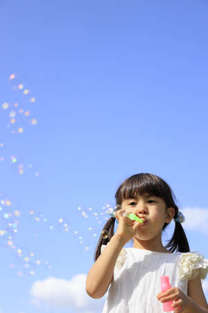 Japanese girl playing with bubble under the blue sky (5 years old)の写真素材