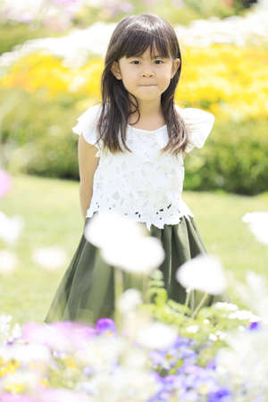 Japanese student girl in flower garden (6 years old)の写真素材
