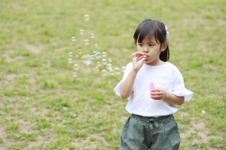 Japanese girl playing with bubble in the green (5 years old)の写真素材