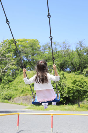 Japanese student girl on the swing (appearance from behind) (6 years old)の写真素材
