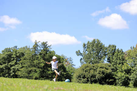 Japanese student girl playing soccer on the grass (6 years old)の写真素材