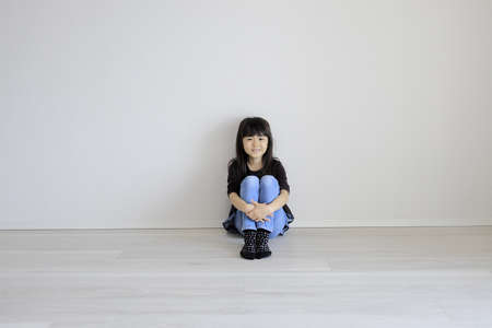 Japanese girl sitting on the floor with grasping knees (7 years old)の写真素材