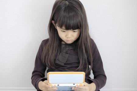Japanese girl playing with video game console on the floor (7 years old)の写真素材