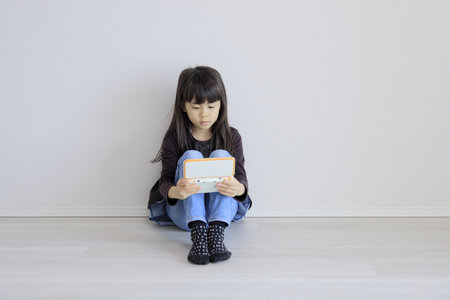 Japanese girl playing with video game console on the floor (7 years old)の写真素材