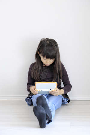 Japanese girl playing with video game console on the floor (7 years old)の写真素材