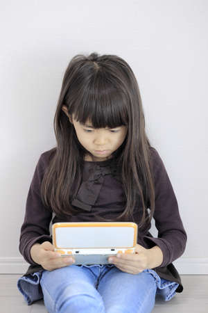 Japanese girl playing with video game console on the floor (7 years old)の写真素材